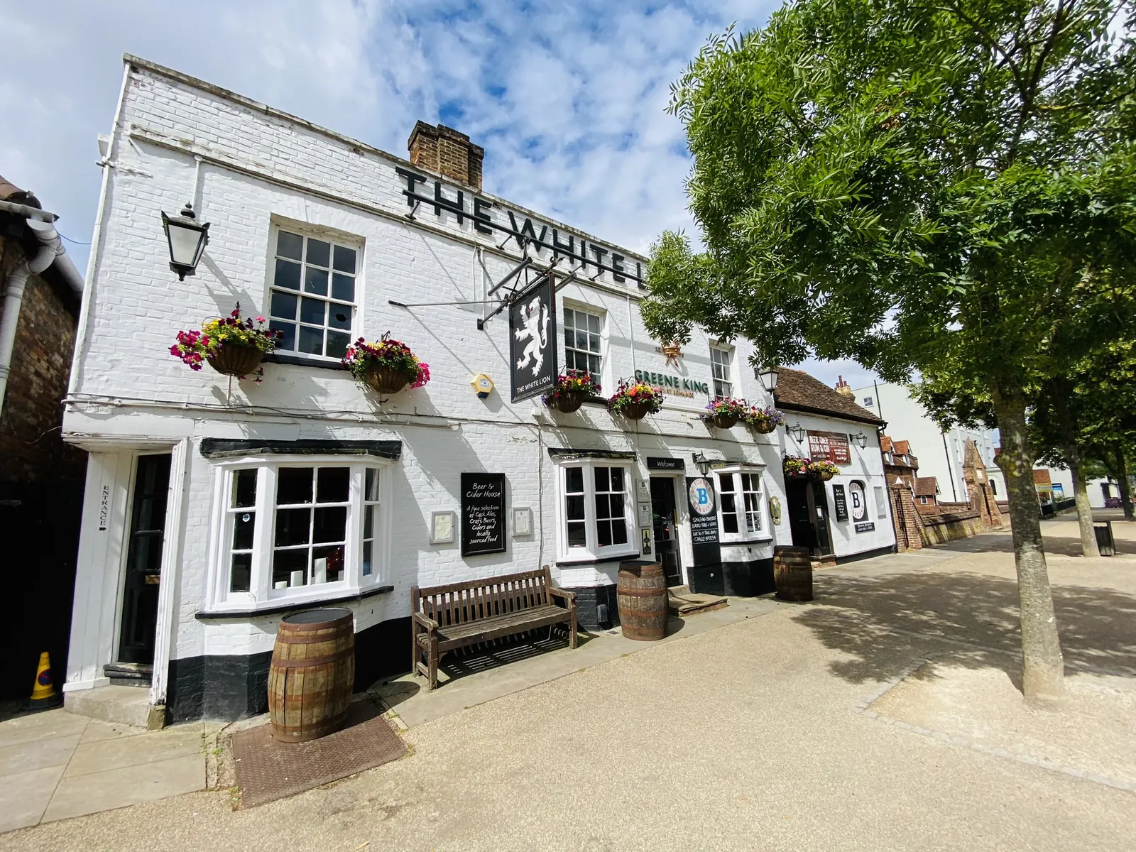 The white rendered frontage of the White Lion on Baldock High Street, with its hanging sign and window boxes